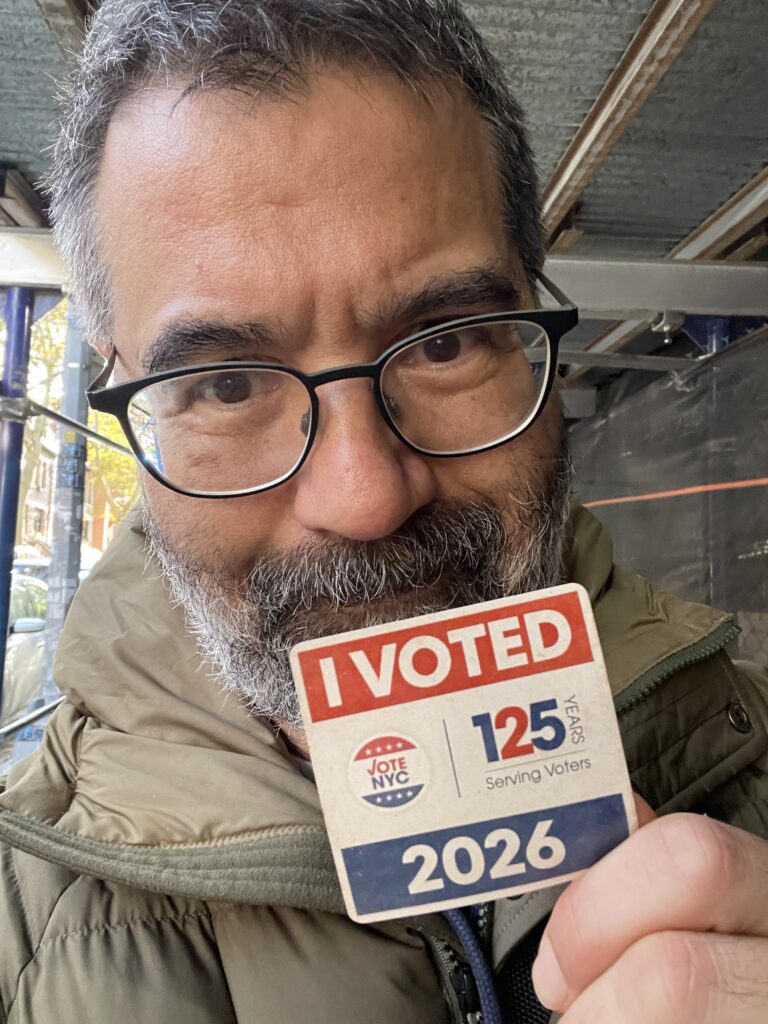 Selfie of Greg Pak smiling and holding up an "I VOTED" sticker
